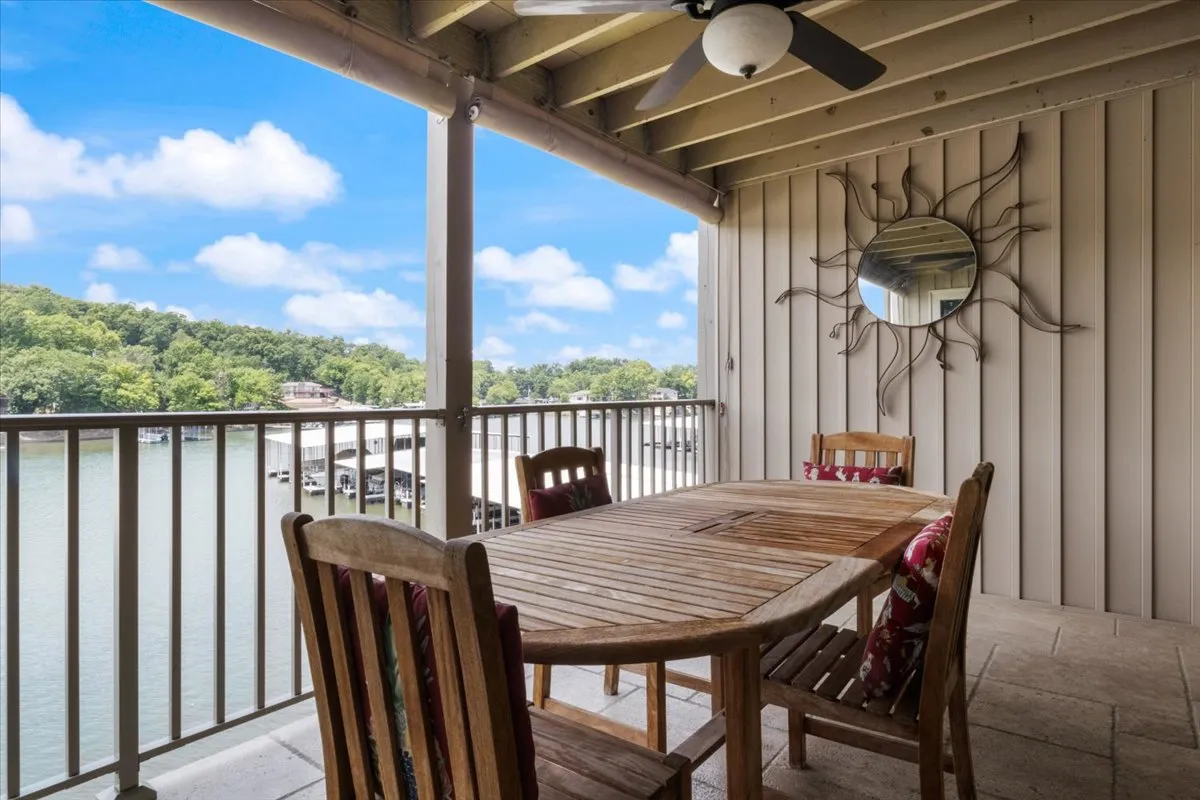 A welcoming exterior dining area featuring a wooden table and chairs, set before a scenic backdrop of water reflecting the vibrant colors of sunset. The atmosphere is casual yet inviting, perfect for outdoor meals and socializing while soaking in the beauty of lake views.