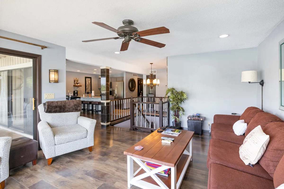 A warm, inviting living area with a comfortable seating arrangement centered around a wooden coffee table and ceiling fan. The open layout encourages relaxation and gathering, suggesting a welcoming and communal space for families or groups.