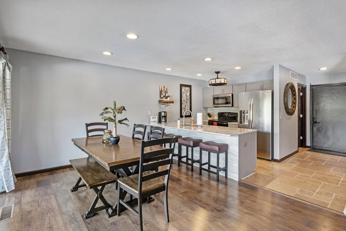 A stylish dining area featuring a spacious table and a kitchen island, accented by decorative wall art. The open layout allows for seamless movement between cooking, dining, and gathering, evoking the communal spirit emphasized in the section.