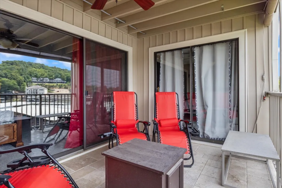 This image features a cozy balcony area with red chairs, glass doors, and a wooden railing, offering inviting views of the surrounding landscape. The setting showcases a private outdoor retreat, easily accessible and visually protected.