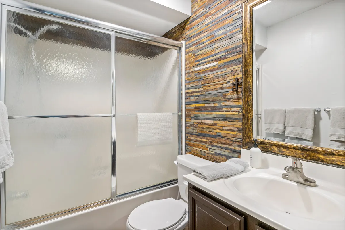 A modern, well-appointed bathroom with a glass-enclosed shower, wooden accent wall, mirrored frame, and stylish vanity sink. The inviting, spa-like atmosphere is perfect for refreshing after a day on the lake or unwinding with a relaxing bath.