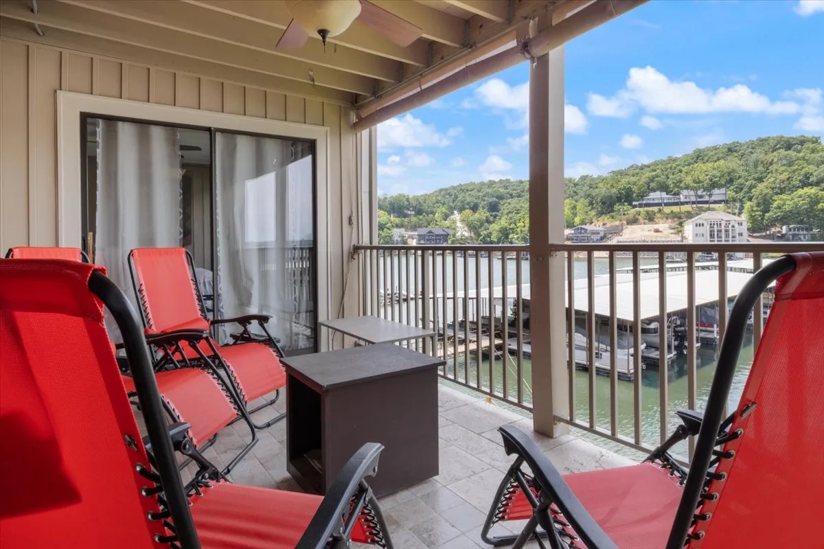 An inviting exterior view of a deck with red lounge chairs and a wooden railing, overlooking the expansive lake. The scene captures a tranquil moment ideal for sunset watching, morning coffee, or unwinding after a day of exploring local attractions.