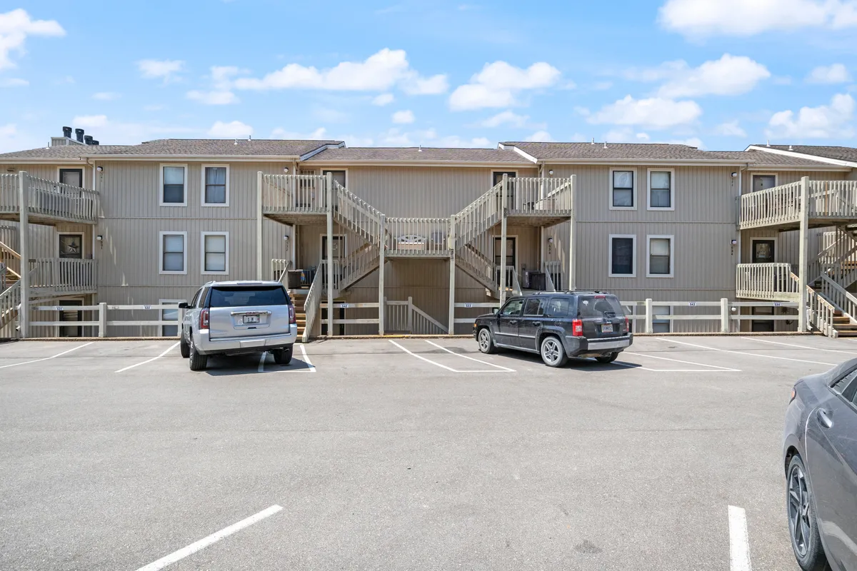 This image depicts the exterior of a two-story apartment building with visible staircases and a parking area. The building's entry points are clearly shown, intuitively referencing the security and smart access features that keep guests safe.